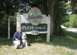 A veterinarian kneels beside a dog in front of a large sign that reads 